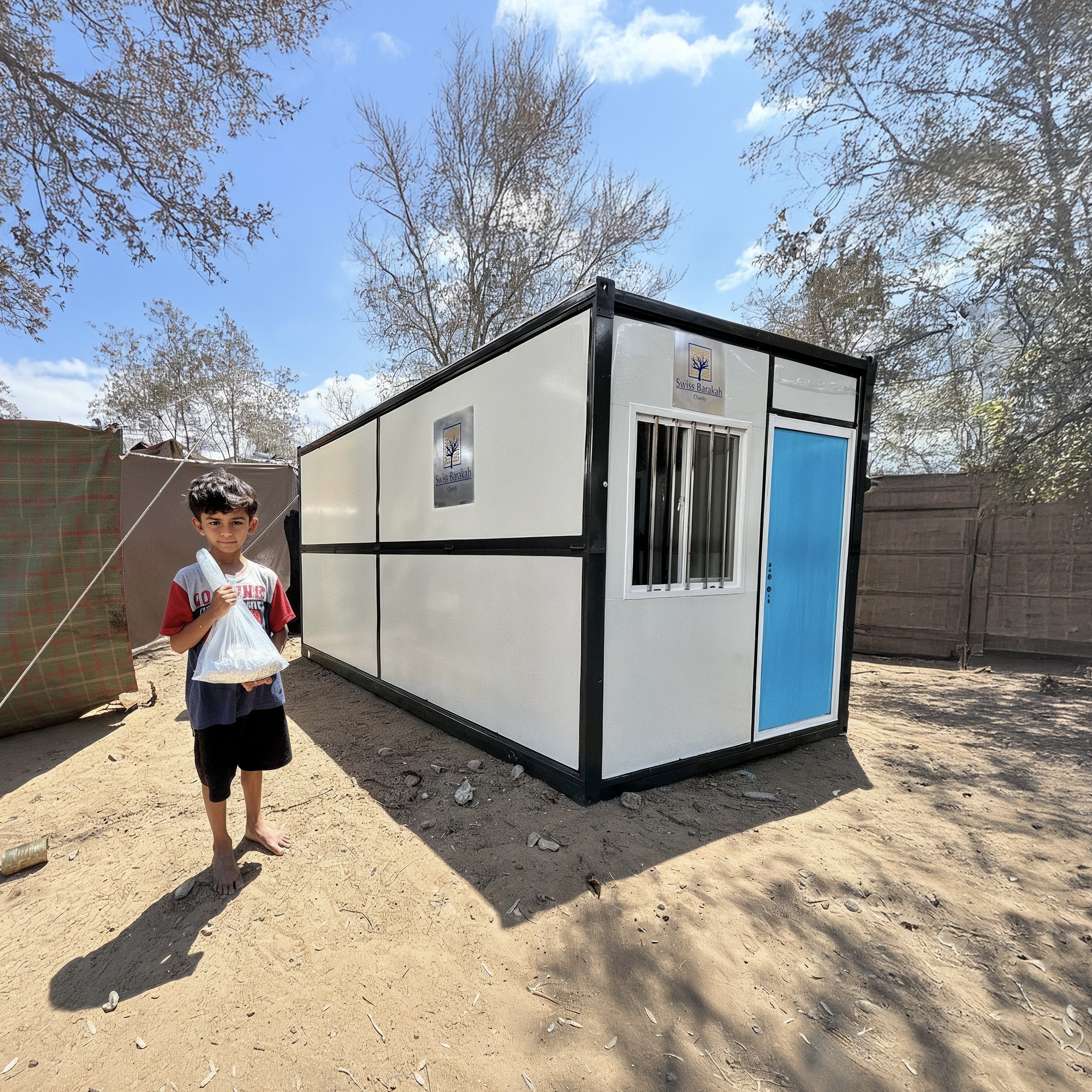 "Young boy in front of a mobile home container for displaced people."