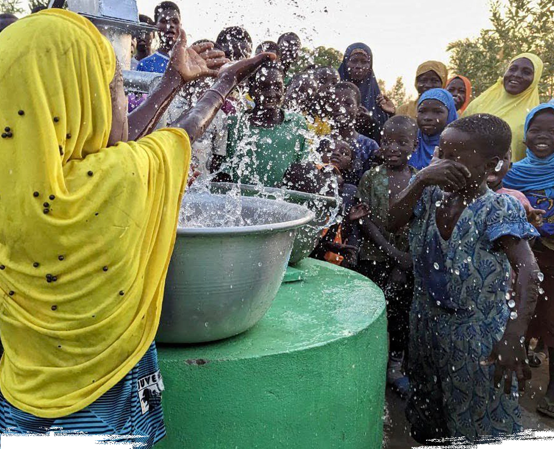 Glückliche Kinder spritzen mit Wasser aus einem Ramadan-Brunnen in Afrika.