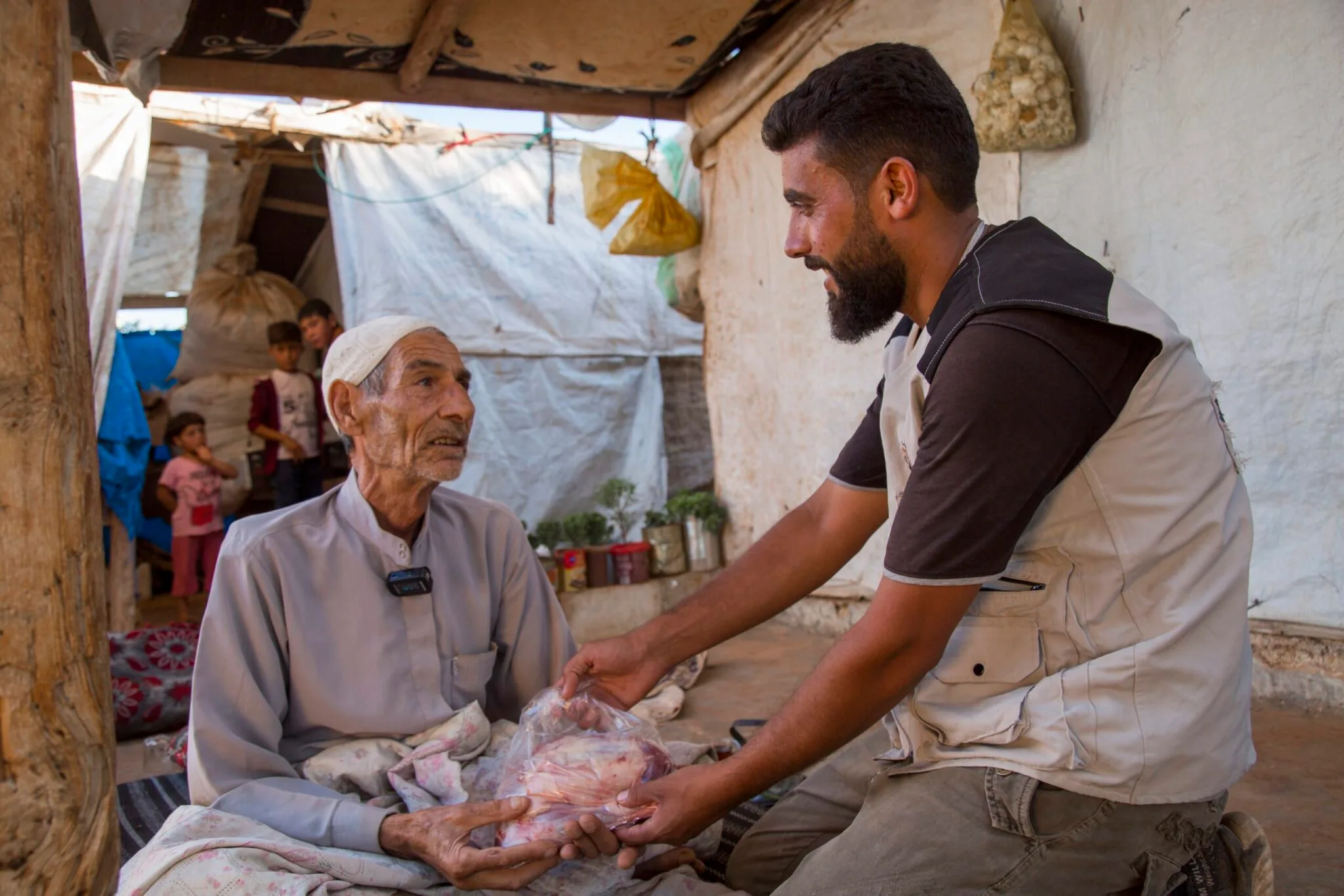 Un operatore umanitario distribuisce carne fresca proveniente dalle donazioni qurban ad anziani bisognosi.