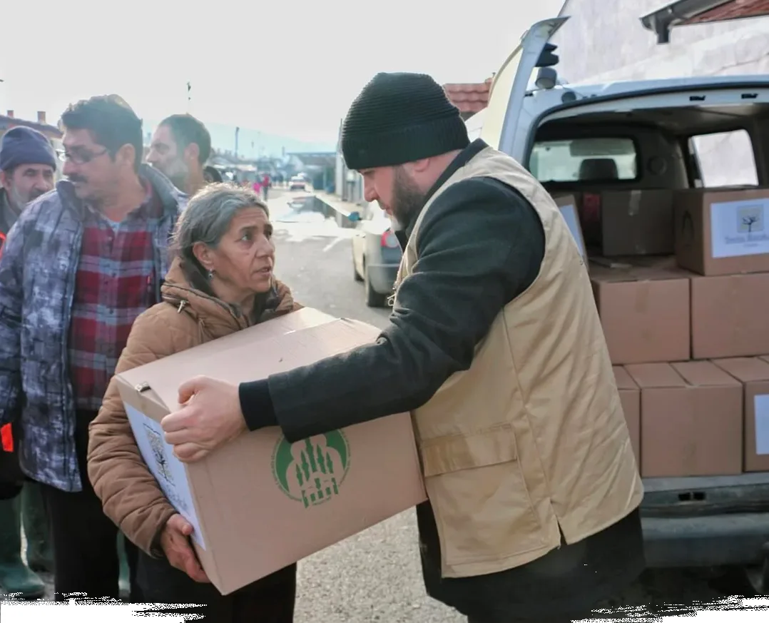 An aid worker hands a box of emergency relief supplies to a woman Kosovo.