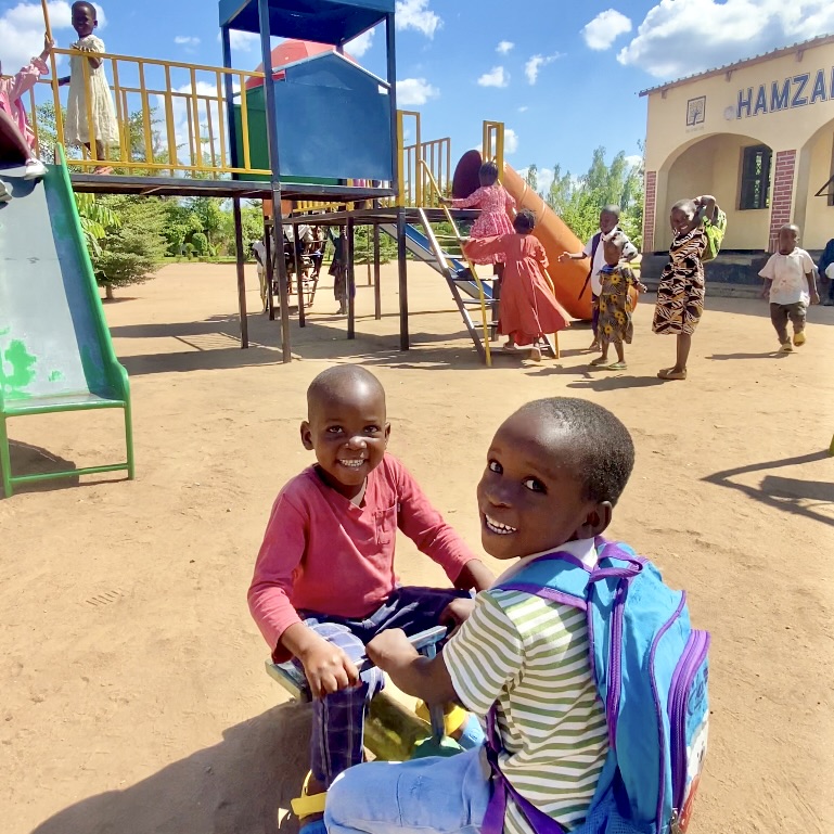 Des enfants orphelins s'amusent sur la balançoire et le toboggan d'un terrain de jeux extérieur.