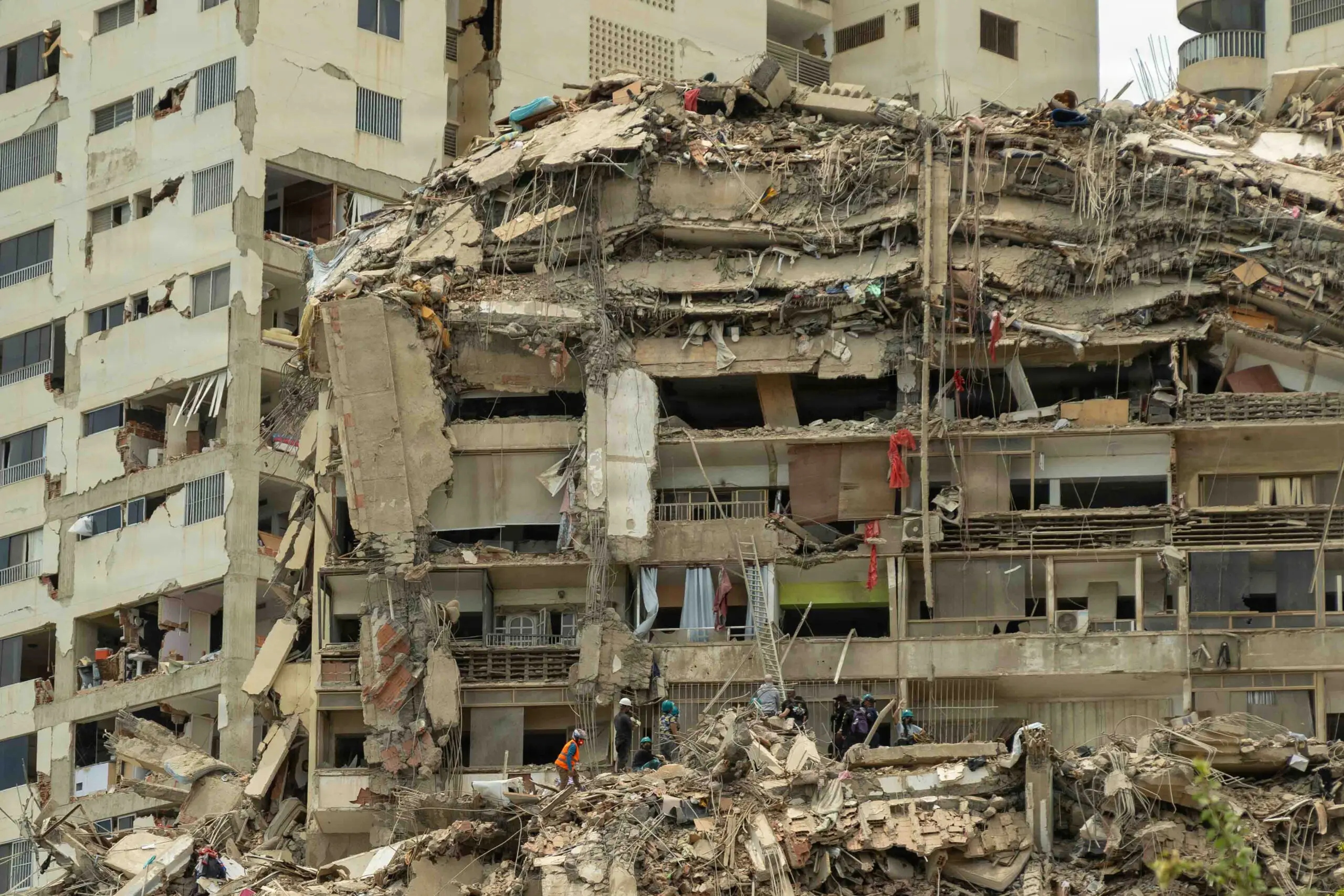 Des secouristes fouillant les décombres massifs d'un immeuble résidentiel de plusieurs étages fortement effondré après un séisme au Venezuela.
